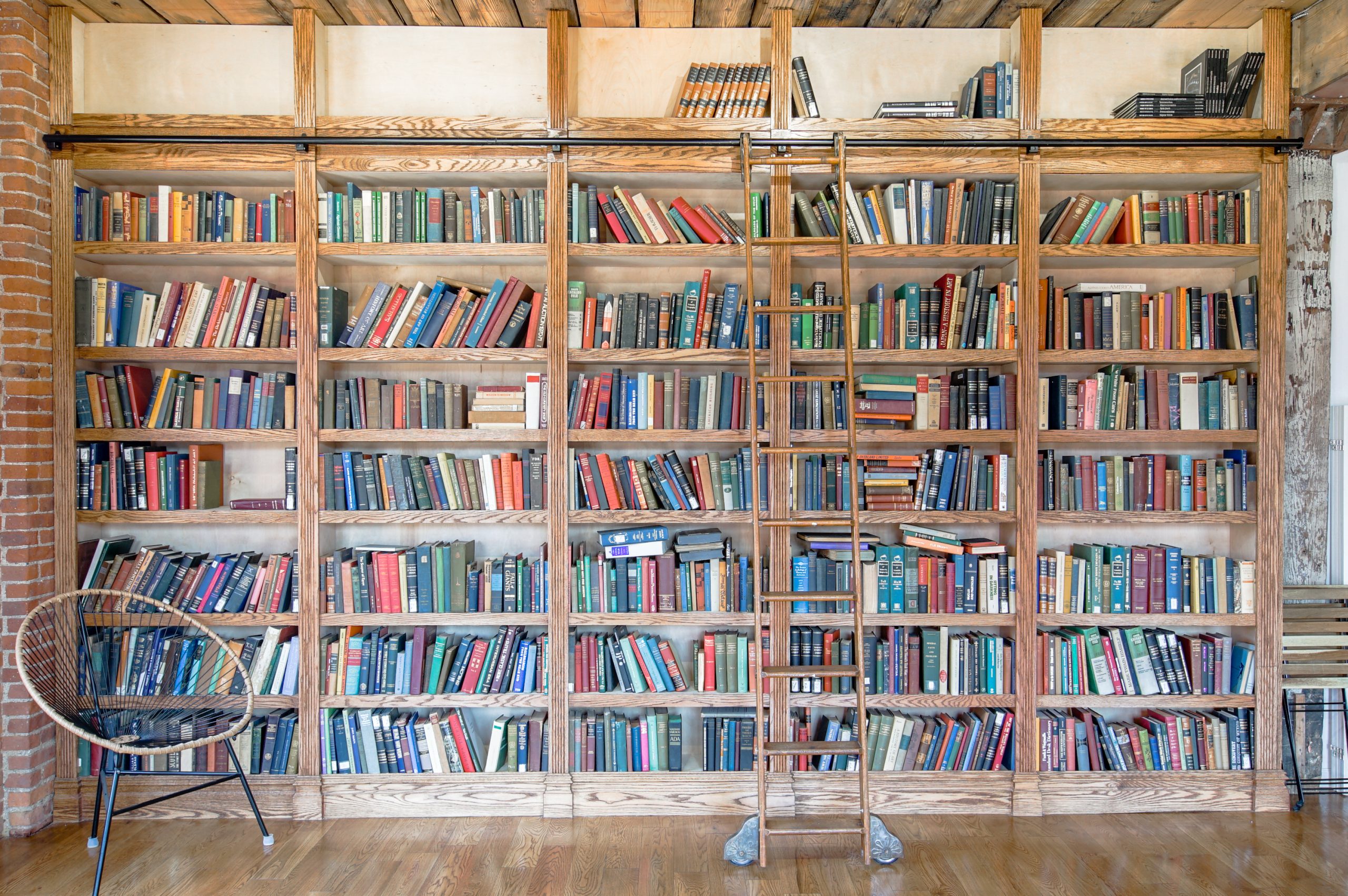 floor to ceiling high bookshelf with ladder filled with books in a photo studio