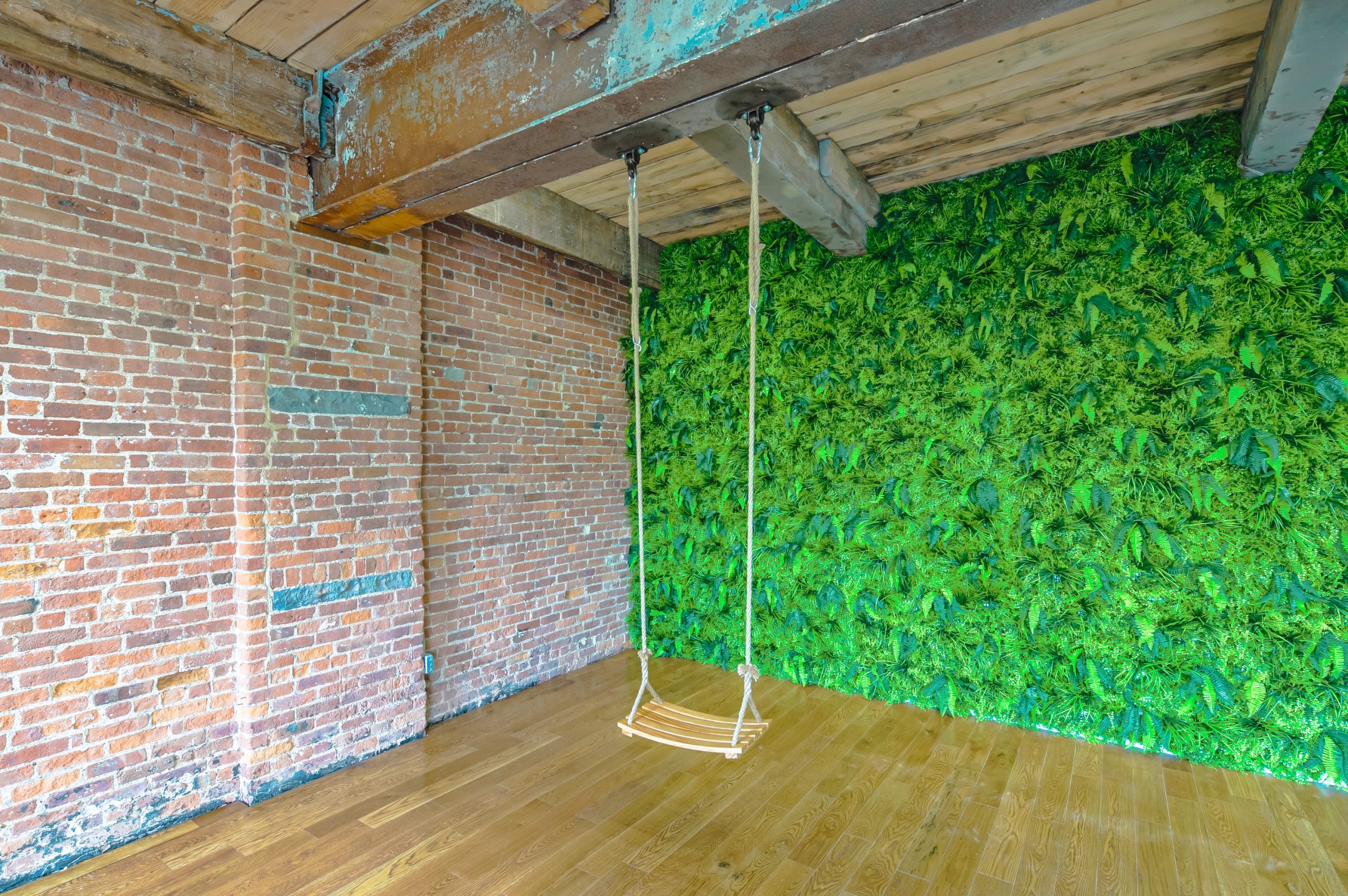 swing with fern filled wall and brick wall in a photo studio