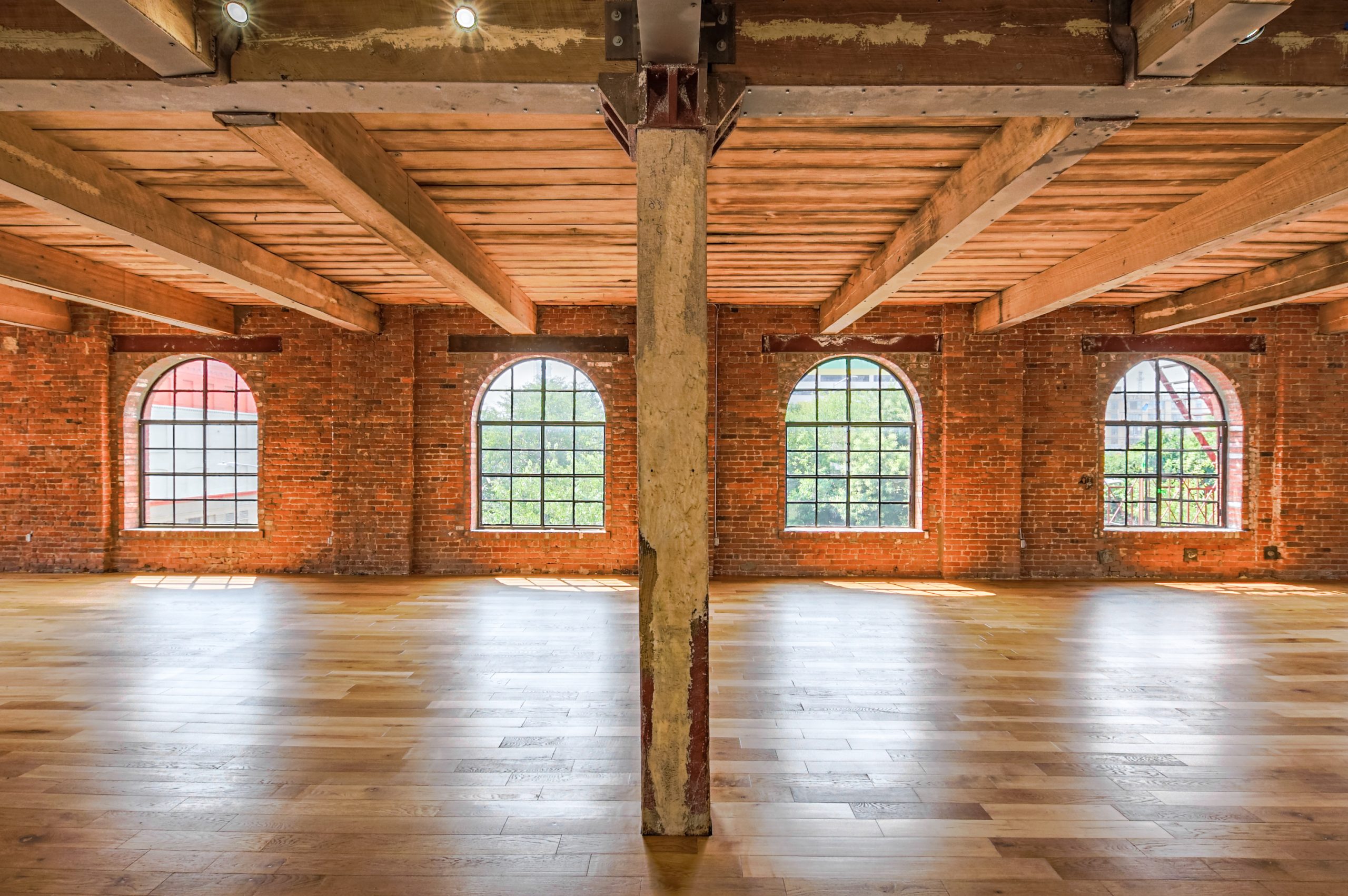 photo studio with four arched windows, brick wall, and wooden floor