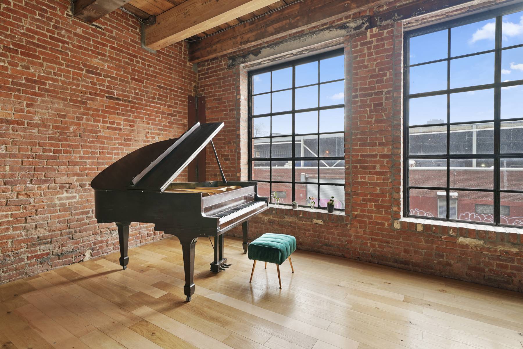 grand piano in a brick wall photo studio with a big window